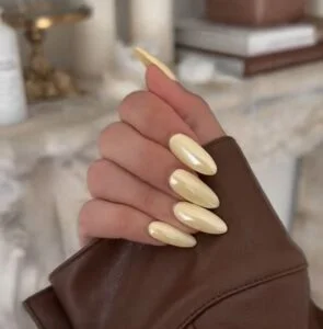 Mão branca com esmalte amarelo-manteiga