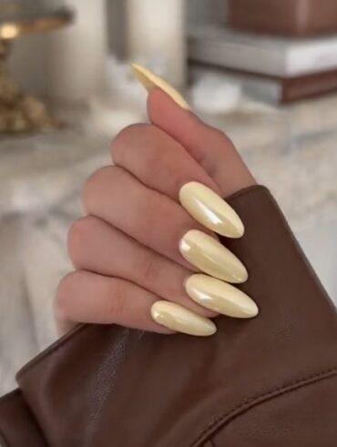Mão branca com esmalte amarelo-manteiga