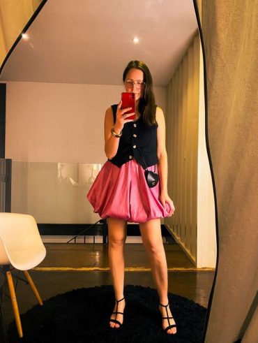 Graciani Dapper usando colete de alfaiataria em cor preta, saia balonê rosa e sandália de salto fino.