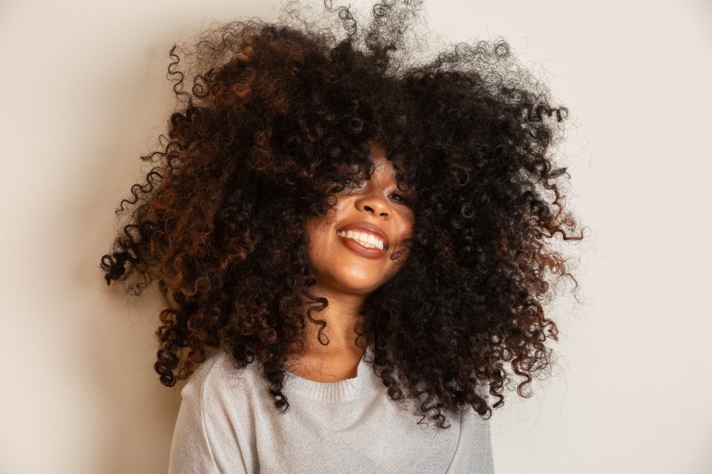 Mulher negra com cabelo crespo e volumoso, com texturas mistas