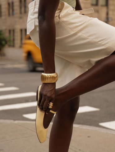 Amy Julliette Lefévre usando bracelete dourado, bermuda de alfaiataria branca e sapatilha amarelo-manteiga