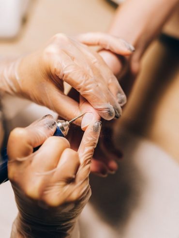 Mãos brancas fazendo a cutícula de outra mãos branca