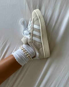 Bérénice usando tênis Adidas, meia branca aparente e tornozeleira de pérolas