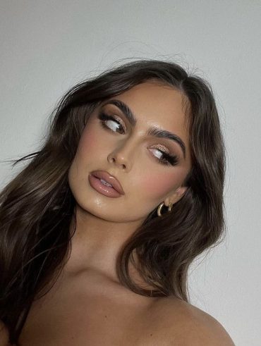 Mulher branca com cabelo escuro, maquiagem marrom e lábios contornados