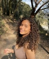 Mulher negra com cabelo morena iluminada cacheado e longo