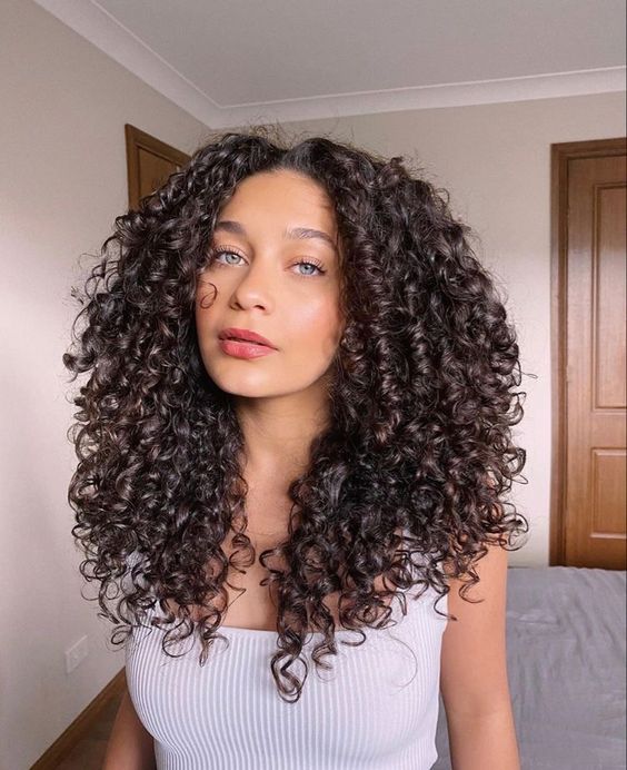 Mulher com cabelo cacheado em camadas longo