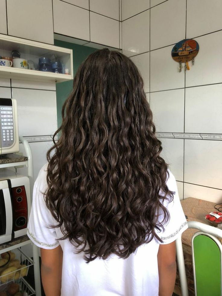 Mulher com cabelo longo e ondulado, de curvatura 2C, com corte em U