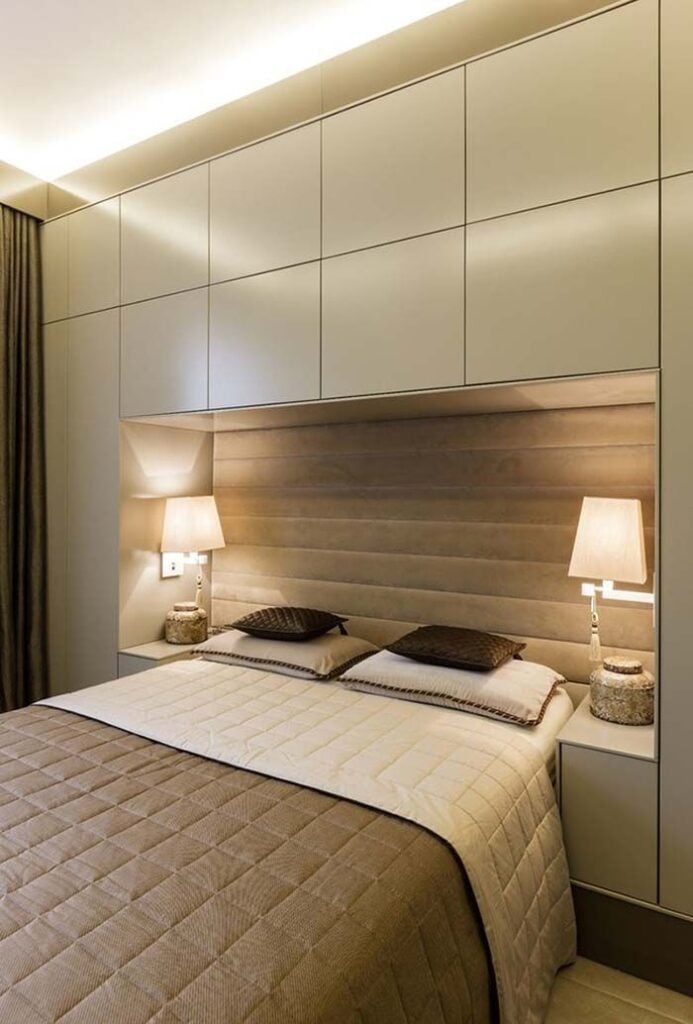 Quarto de casal com cores neutras e luminárias ao lado da cama