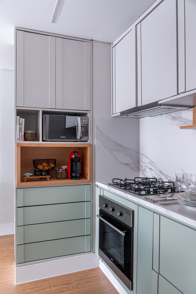 Cozinha com armários cinza e verde menta, com mesa pequena