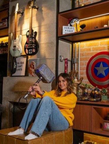 Mari Palma sentada em parte de sua casa com decoração geek
