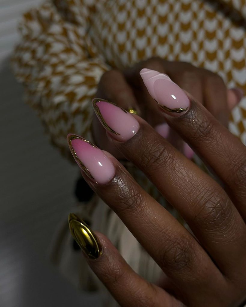 Mão negra com unha stiletto rosa com decoração em dourado 