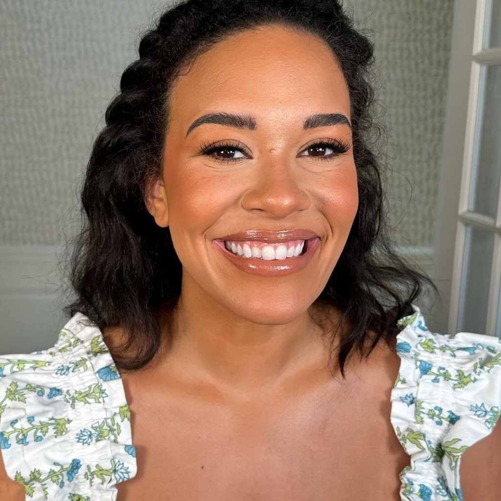 Mulher negra com vestido, cabelo escuro e maquiagem natural