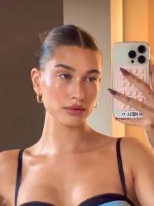 Hailey Bieber com vestido de alcinha, coque e pele "molhada"