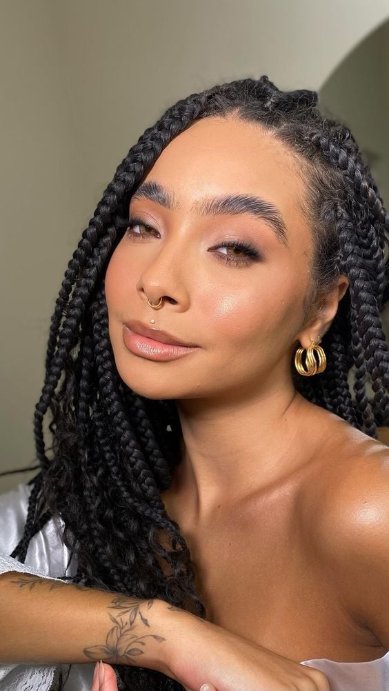Mulher de pele negra com tranças e maquiagem clean 