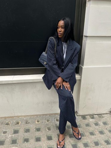 Marilyn usando conjunto de blazer e calça de alfaiataria risca de giz azul marinho, bolsa Chanel matelassê e chinelo Chanel