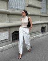 Mary usando óculos de sol, blusa de tricô gola alta off-white, calça de alfaiataria branca e chinelo kitten heels