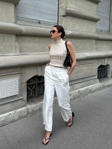 Mary usando óculos de sol, blusa de tricô gola alta off-white, calça de alfaiataria branca e chinelo kitten heels