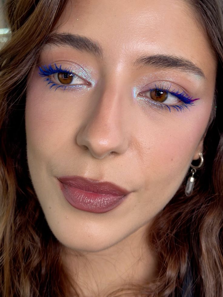 Mulher branca com cabelo castanho, maquiagem com cílios azul