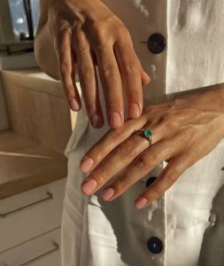 Mãos brancas com anel verde e naked nails