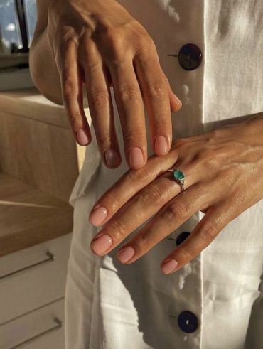 Mãos brancas com anel verde e naked nails