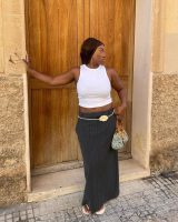 Nnenna usando regata branca, saia midi risca de giz cinza, cinto de flor e chinelo de dedo