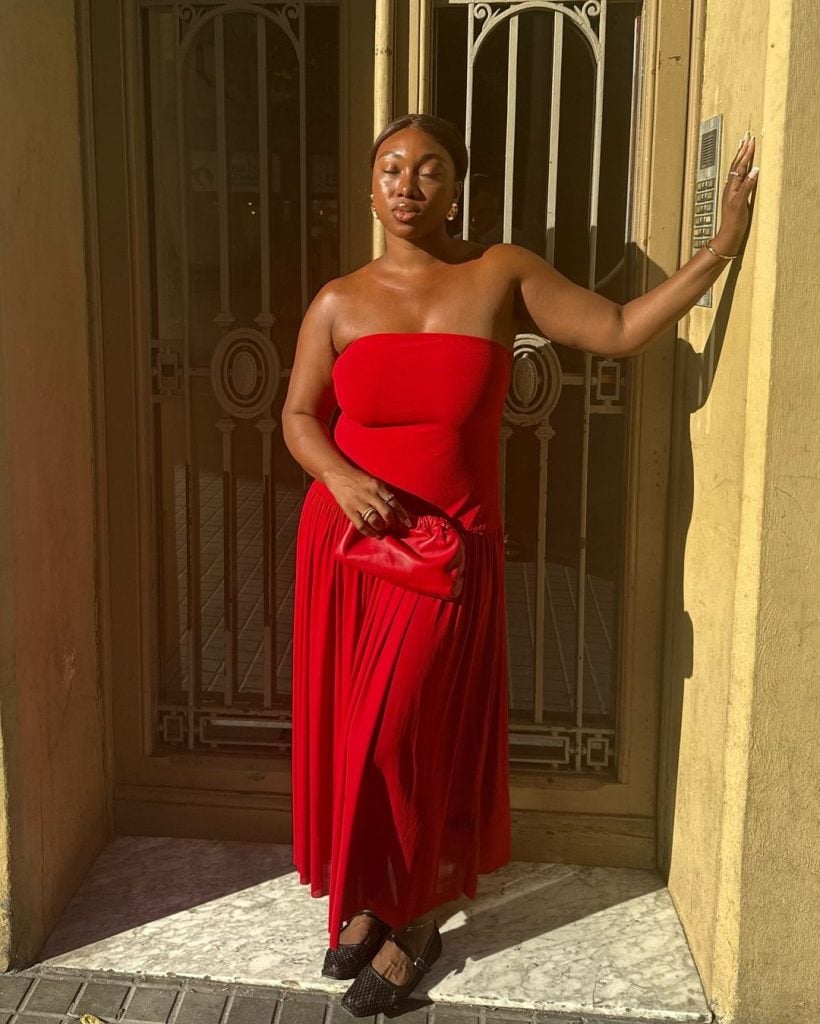 Nnenna usando vestido de cintura baixa sem alça vermelho, bolsa vermelha e sapatilha Mary Jane preta