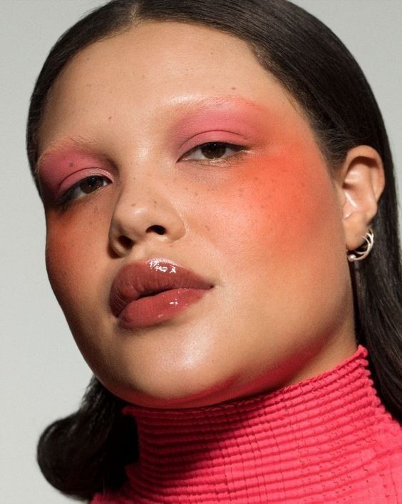 Mulher branca com roupa rosa, blush laranja e sombra rosa pastel
