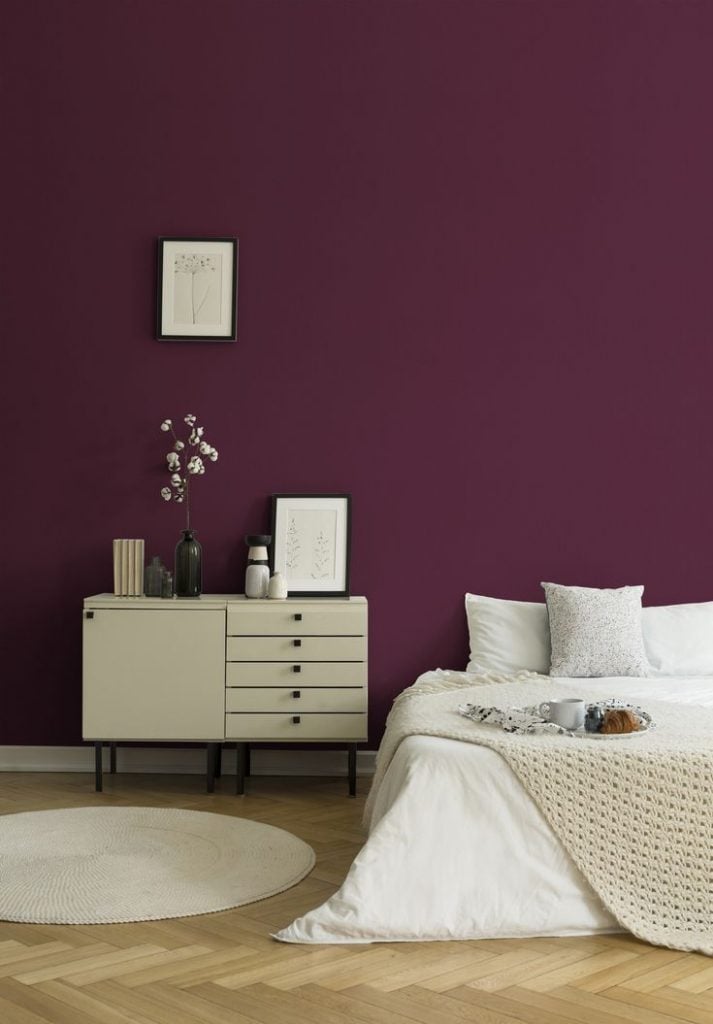 Quarto com parede roxa e móveis em tons neutros