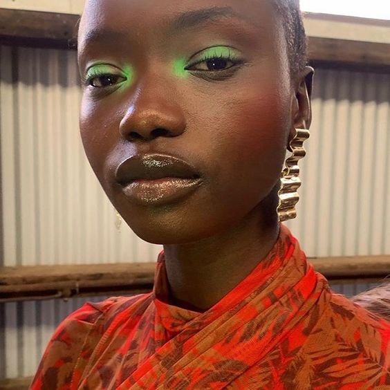 Mulher negra com roupa estampada e maquiagem com sombra verde pastel