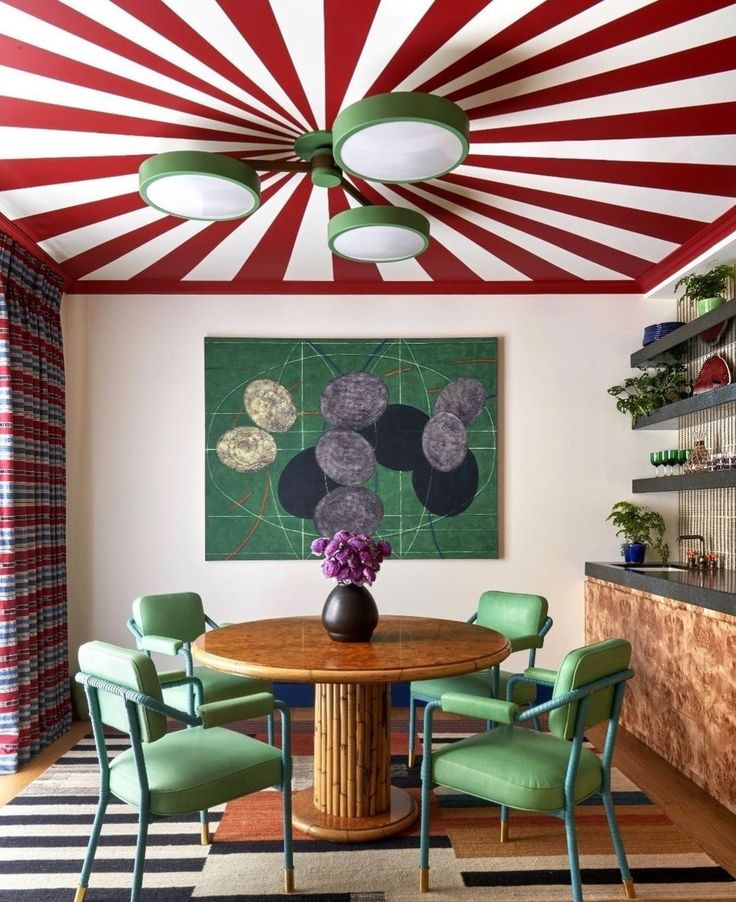 Espaço com mesa marrom, cadeiras verdes e teto em vermelho e branco