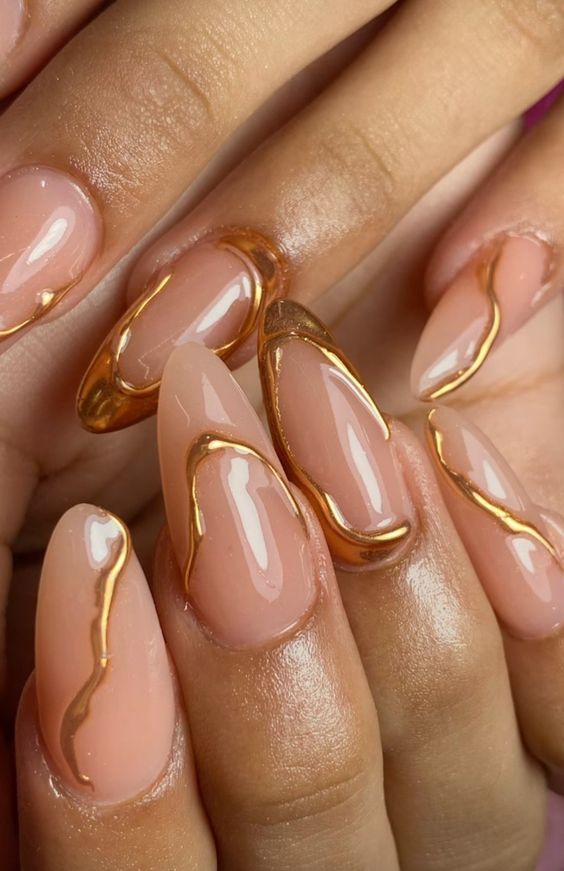 Mãos branca com unha stiletto nude com aplicações em dourado 