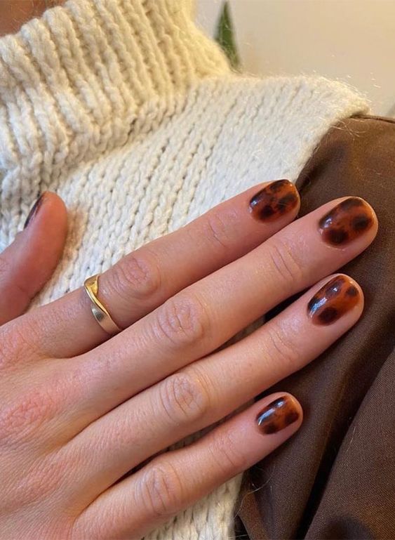 Mão branca com anel dourado e unha curtinha com estampa de tartaruga
