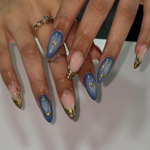 Mãos brancas com anéis dourados e unha stiletto azul-celeste com decorações em dourado