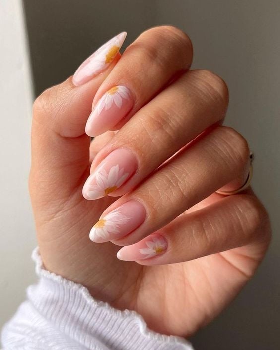 Mão branca curvada com unha decorada com margaridas 