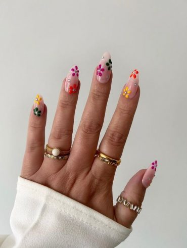 Mão branca com anéis e unha amendoada com flores coloridas e aplicações