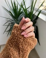 Mão branca curvada com unha amendoada média nude rosada com decoração metálica