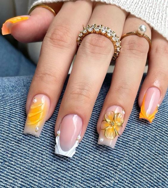Mão branca com anéis e unha quadrada com francesinha branca, aura nail amarela e flor de hibisco em alto relevo amarela 