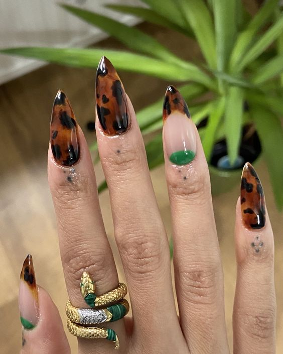Mão branca com anel e unha de tartaruga stiletto com francesinha inversa verde