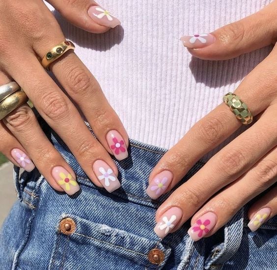 Mãos brancas com anéis e unhas florais coloridas 