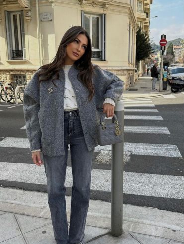 Mulher jovem e magra de pele clara e cabelos castanhos com look cinza.
