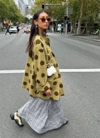 Mulher jovem de pele clara com cabelo escuro. Ela usa camisa com estampa.