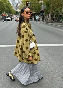 Mulher jovem de pele clara com cabelo escuro. Ela usa camisa com estampa.