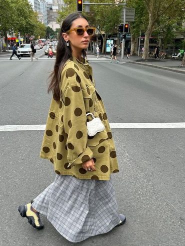 Mulher jovem de pele clara com cabelo escuro. Ela usa camisa com estampa.