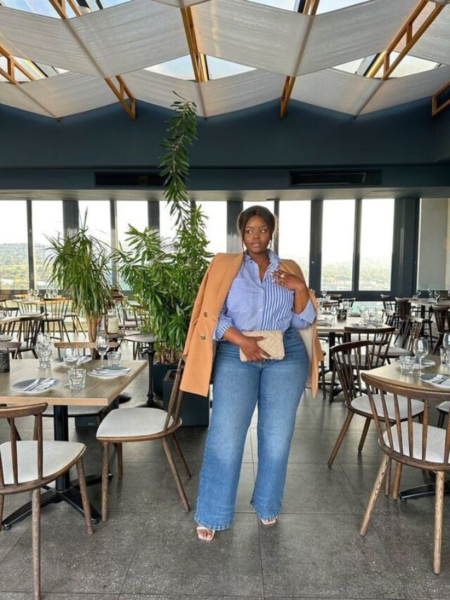 Mulher jovem, negra e gorda, com cabelo preso, usando camisa azul, blazer bege claro e calça jeans.