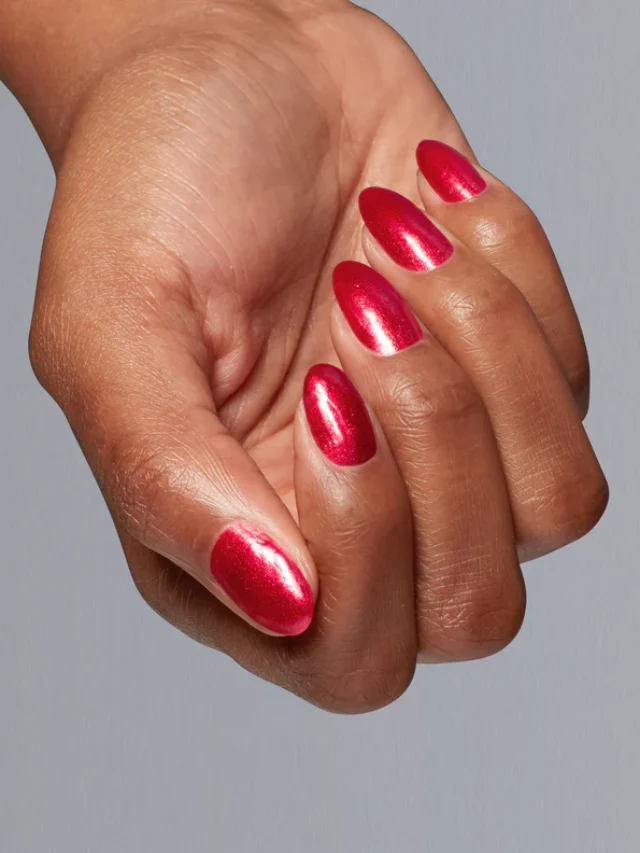 Mão de pele branca, com esmalte vermelho metálico OPI Big Zodiac Energy Kiss My Aries