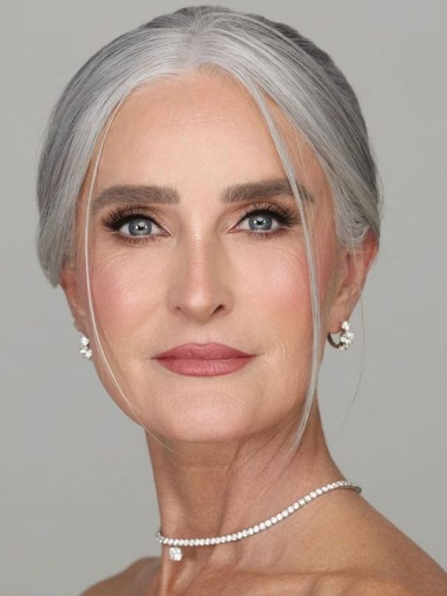 Mulher mais velha com cabelo grisalho preso e maquiagem