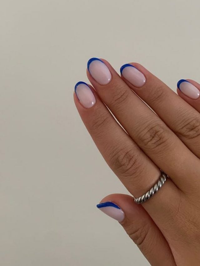 Mulher com a mão branca, com esmalte branco e francesinha azul nas unhas curtas