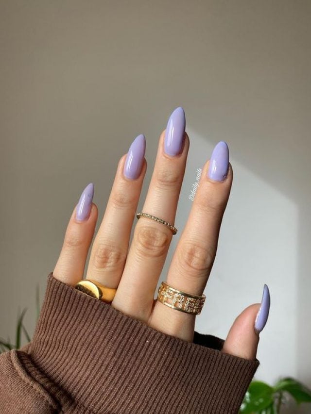 Mão branca com anéis, manga marrom e unha longa stiletto lavanda
