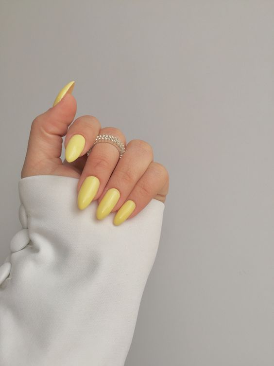 Mão branca com esmalte amarelo-manteiga