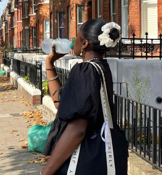 Mulher jovem de pele escura. Ela está virada de costas e usa scrunchie branco.